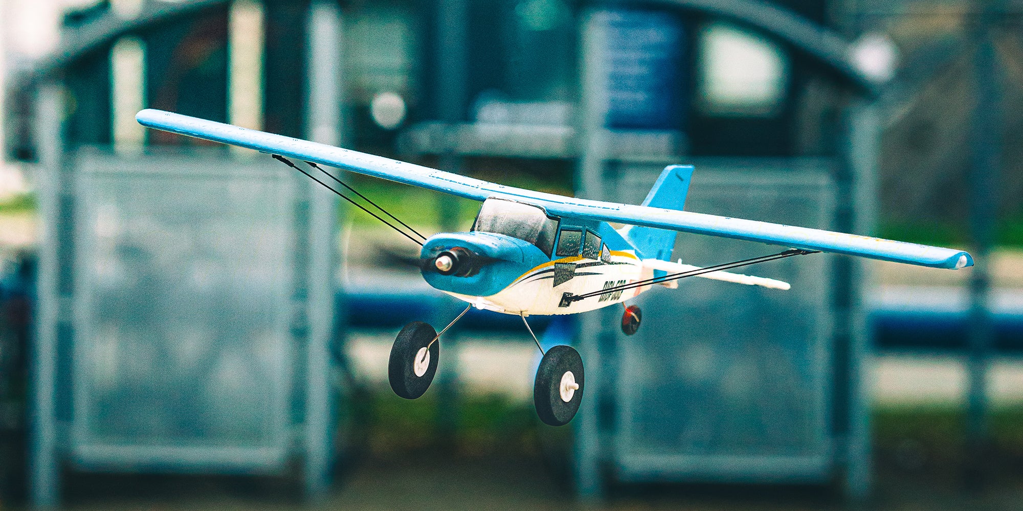 Gult QIDI-560 Brushless sportsfly i flot flyvning lavt over en grøn mark i dagslys.