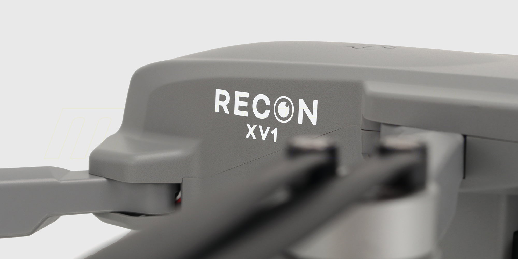 GrÄ Drone Recon XV1 med foldbare arme og kamera set skrÄt forfra pÄ hvid baggrund.