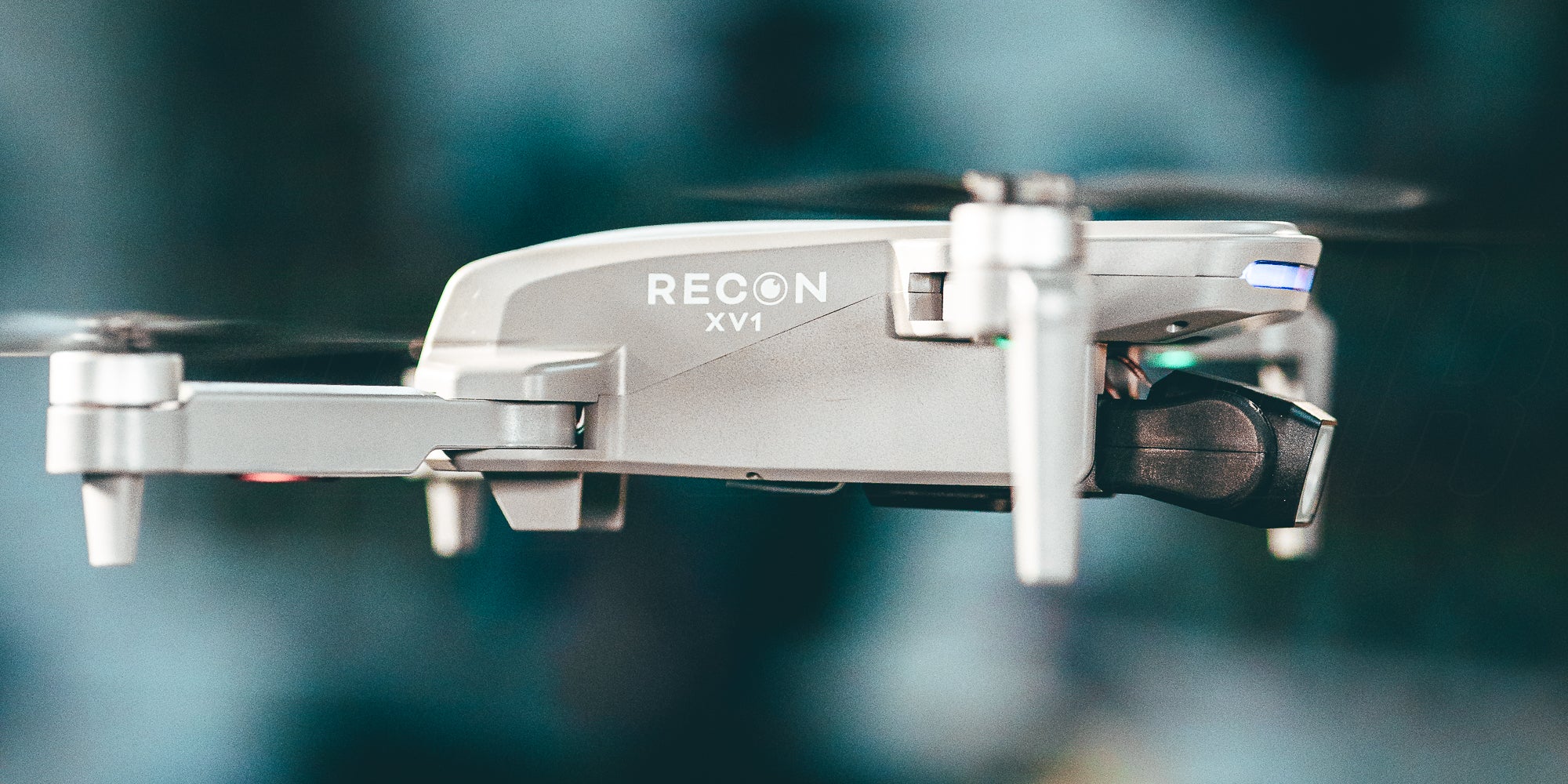 Sort Drone Recon XV1 i luften over en grĂŠsmark med tĂŠndte LED-lys.
