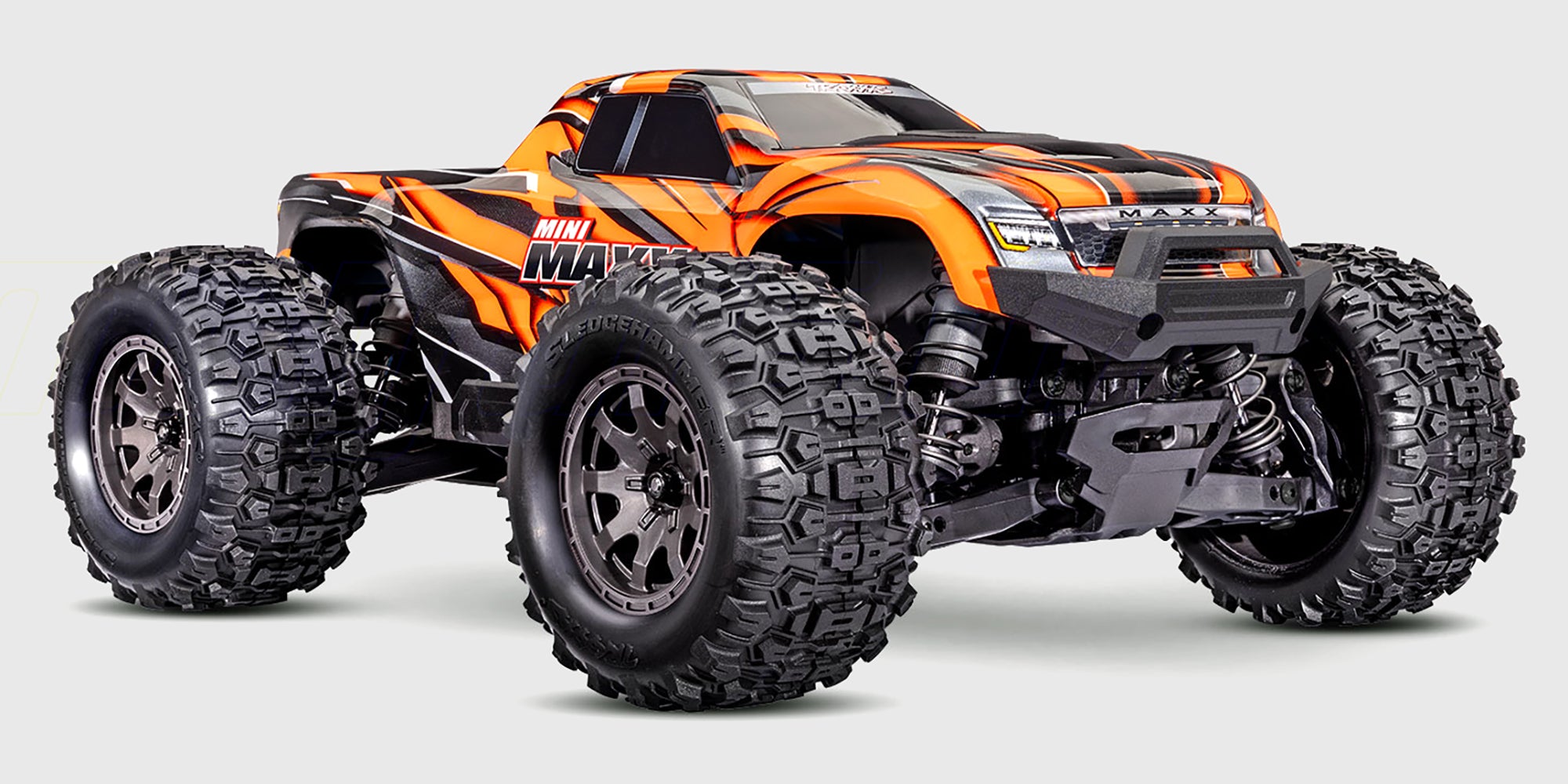 Blå Traxxas Mini Maxx monster truck med robuste hjul og kraftfuld affjedring set skråt forfra på hvid baggrund.