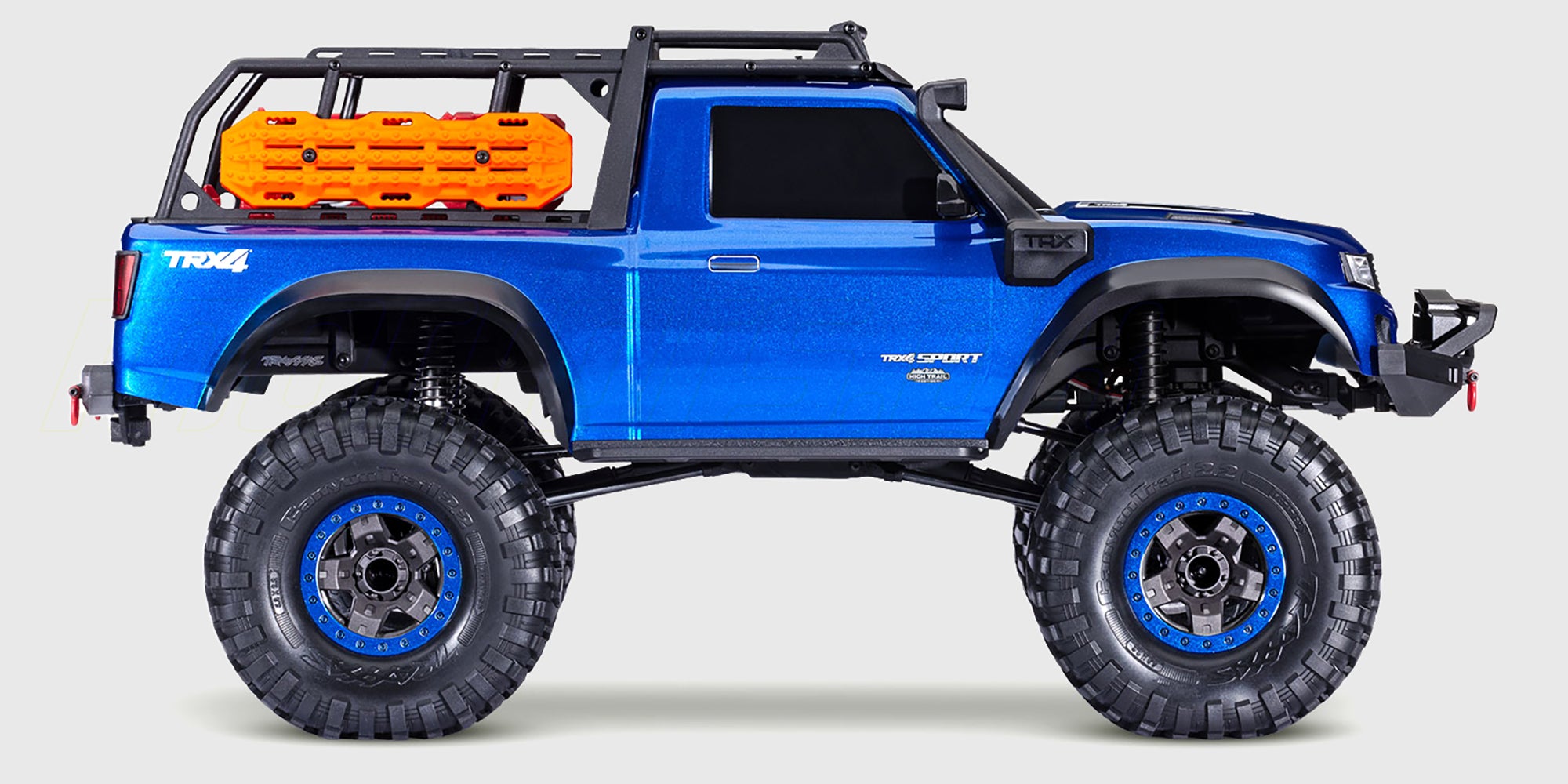 Traxxas TRX-4 Sport High Trail i blå med hævet undervogn og offroad-dæk kører gennem vand og mudder.