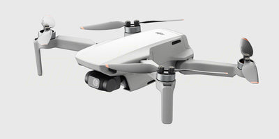 DJI Mini 4K drone med udfoldede arme og propeller set forfra på en hvid baggrund.