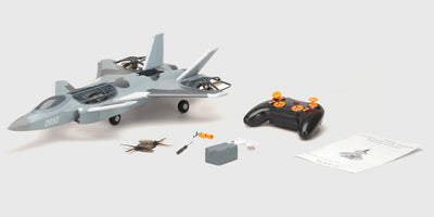 Grå Fighter Jet Brushless fjernstyret fly vist i sin kasse med tilhørende fjernbetjening og tilbehør.
