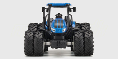 Grøn fjernstyret traktor med gul frontlæsser og fjernbetjening vist på hvid baggrund.