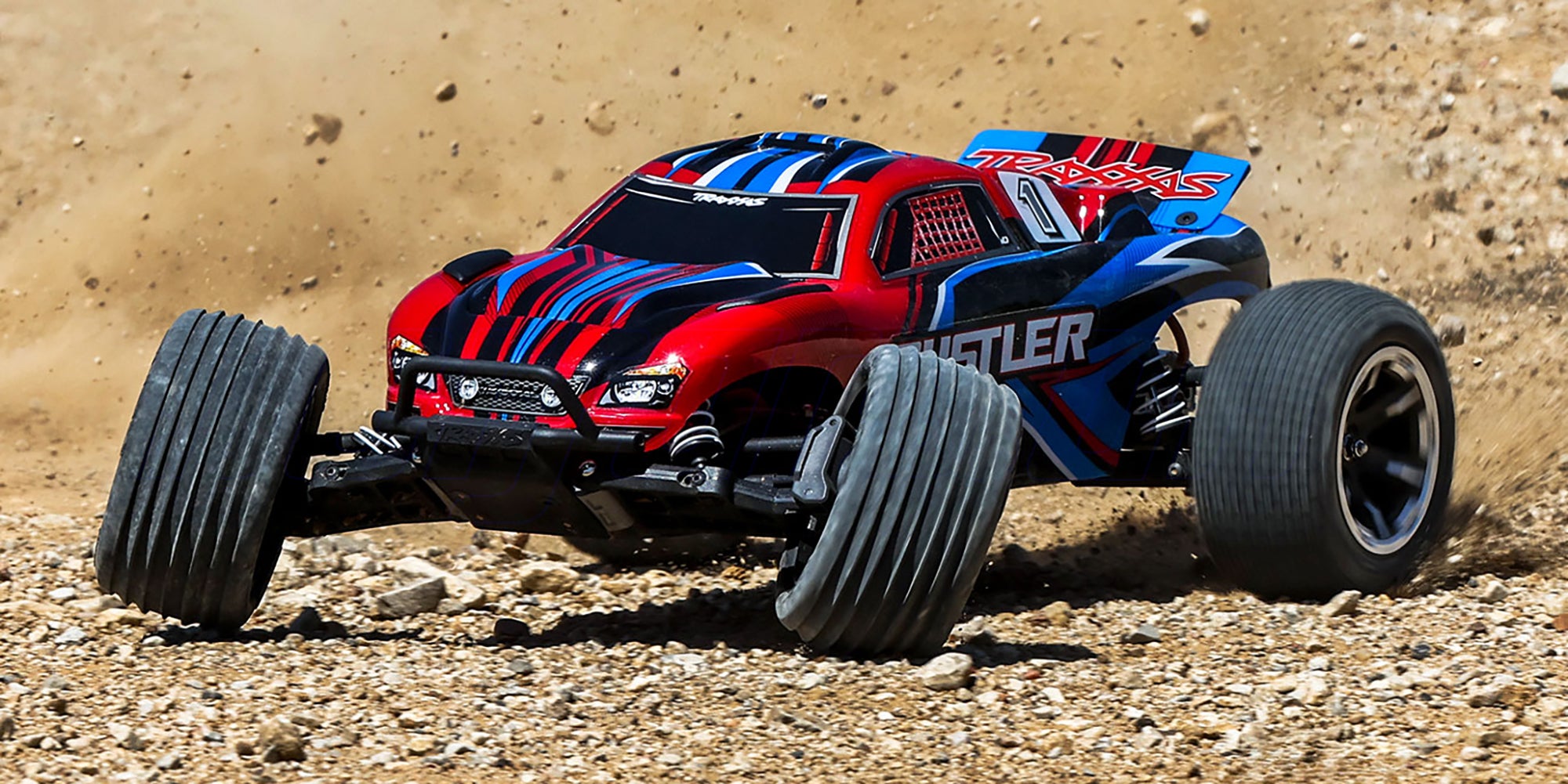 Blå Traxxas Rustler 2WD fjernstyret stadiontruck med grove offroad-dæk set forfra på hvid baggrund.